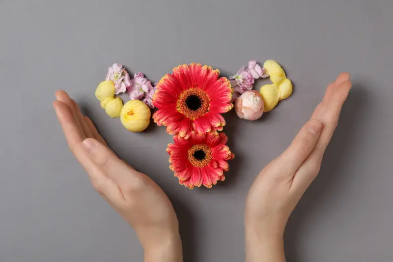 Floral uterus made of red and yellow flowers with hands around it, symbolizing fertility preservation for cancer patients