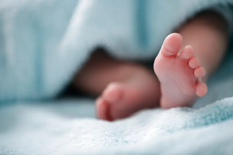 Baby feet wrapped in a soft blue blanket — representing the outcome of a surrogacy journey