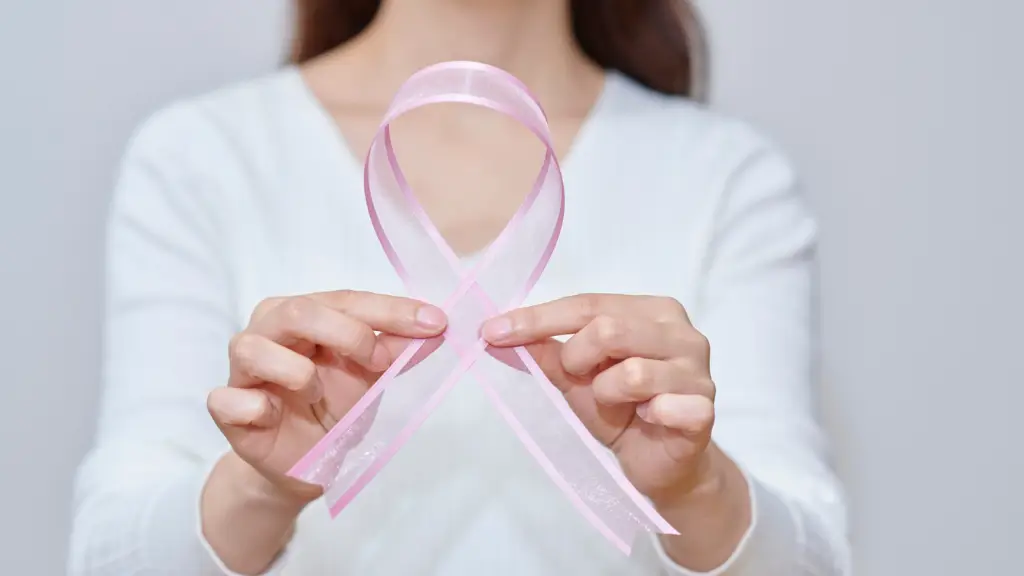 Survivor holding a pink ribbon for breast cancer awareness