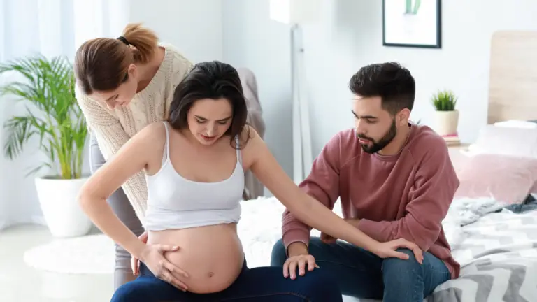 Pregnant gestational surrogate sitting with intended parents during the surrogacy journey